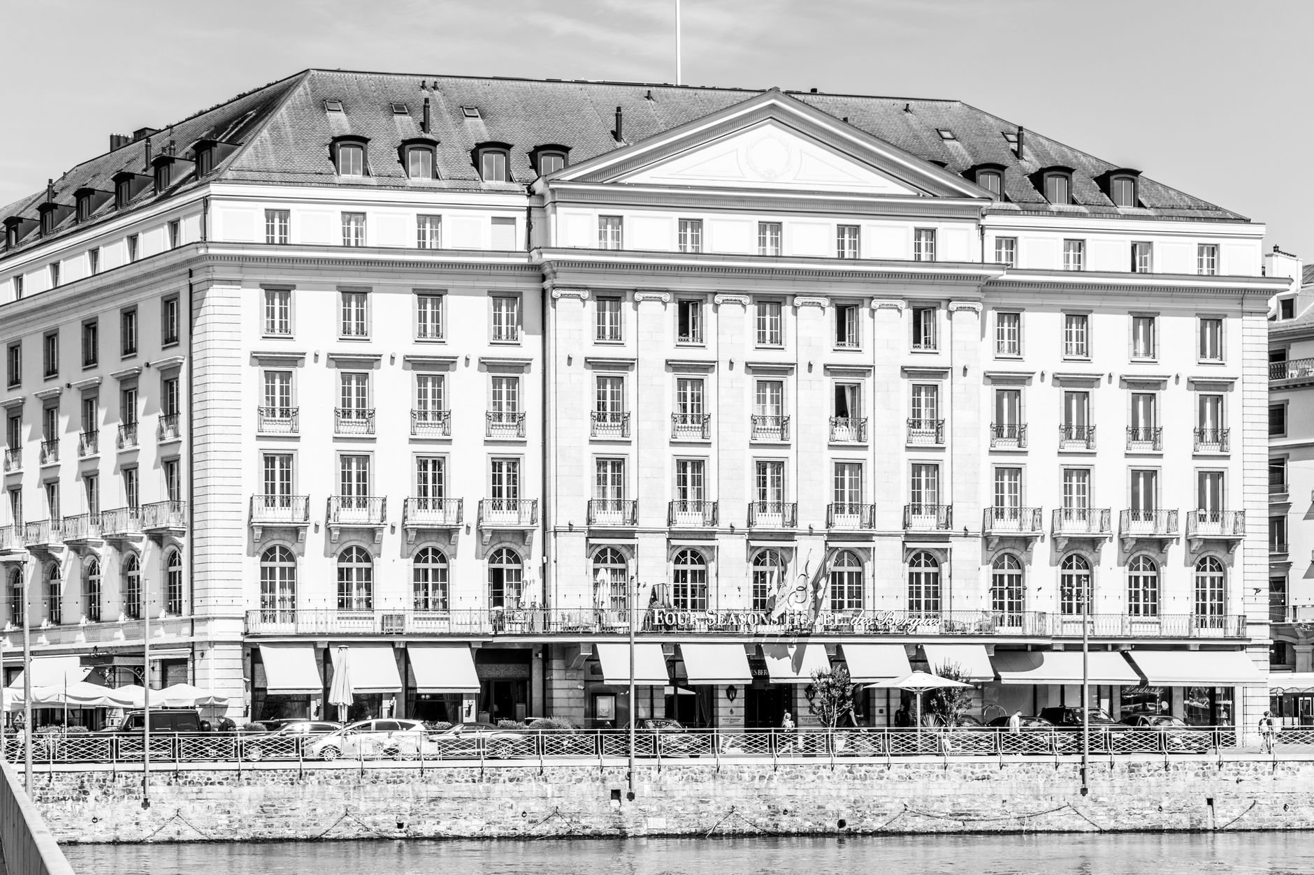 Elegant historic building facade in Geneva, reflected on lake waters.